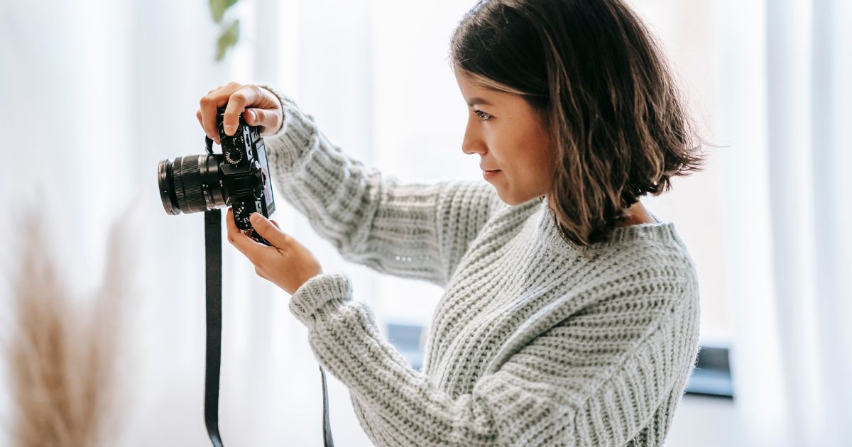 Woman with short dark hair and a sweater taking a photo of the interior of a vacation home with a camera.