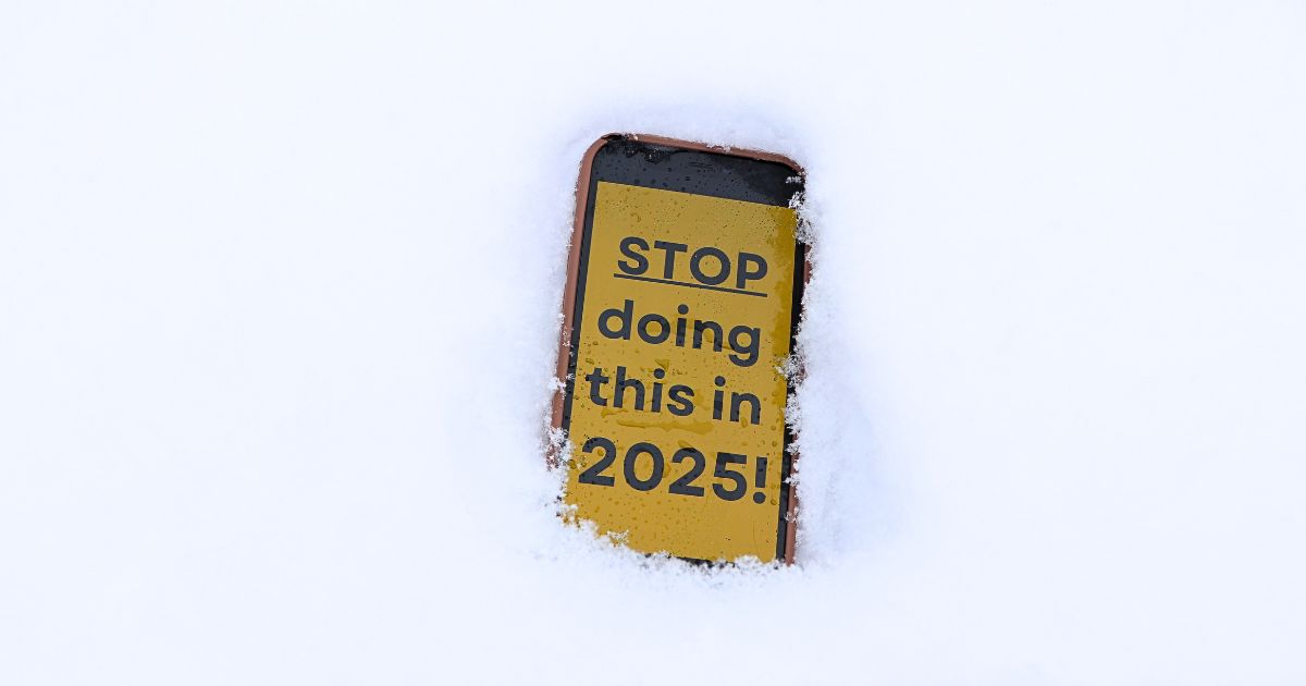 Phone in the snow with black text on a yellow screen that says "STOP doing this in 2025"